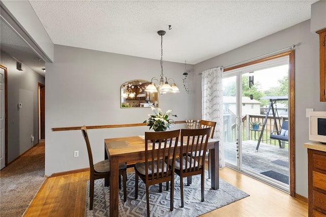215 SE Country Ln, Lees Summit, MO 64063 - dining area featuring light wood-style floors, a chandelier, a textured ceiling, and baseboards