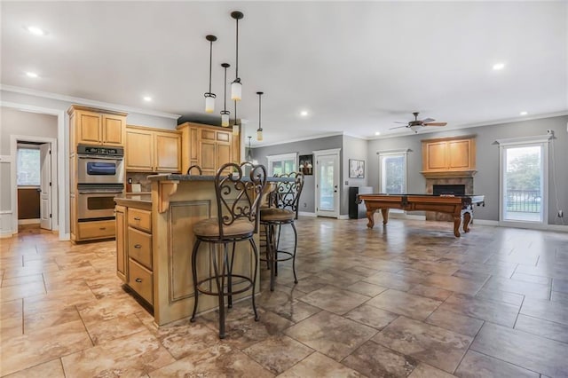 13808 Richards St, Overland Park, KS 66221 - kitchen with double oven, crown molding, baseboards, a breakfast bar, and a ceiling fan