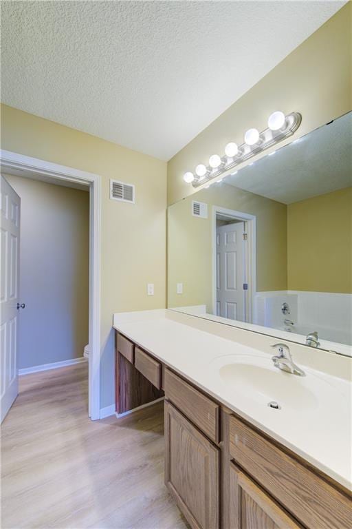 8815 Timber Creek Ln, Pleasant Valley, MO 64068 - bathroom with wood finished floors, vanity, baseboards, toilet, and a textured ceiling