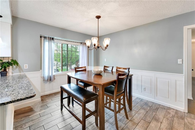 530 Nipper Ln, Leavenworth, KS 66048 - dining space featuring wood finish floors, a textured ceiling, a chandelier, a wainscoted wall, and a decorative wall
