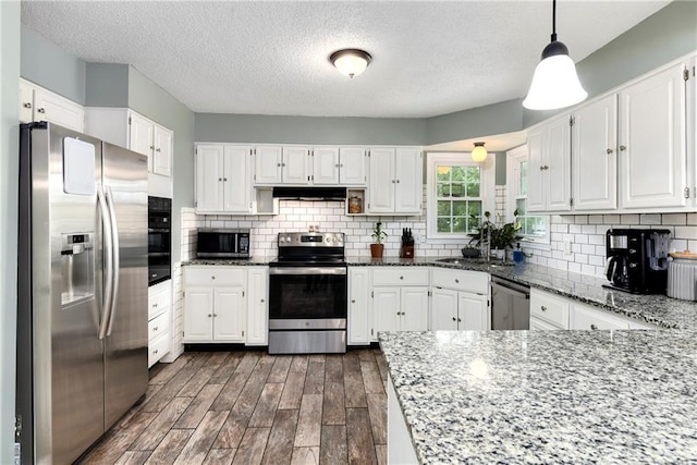 530 Nipper Ln, Leavenworth, KS 66048 - kitchen featuring stainless steel appliances, under cabinet range hood, dark stone countertops, white cabinets, and a textured ceiling