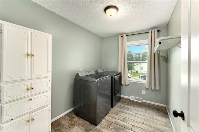 530 Nipper Ln, Leavenworth, KS 66048 - washroom with washing machine and dryer, a textured ceiling, light wood-type flooring, cabinet space, and baseboards