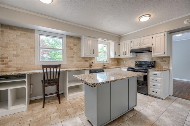 12800 W 100th St, Lenexa, KS 66215 - kitchen with black electric range, under cabinet range hood, light stone counters, white cabinets, and decorative backsplash