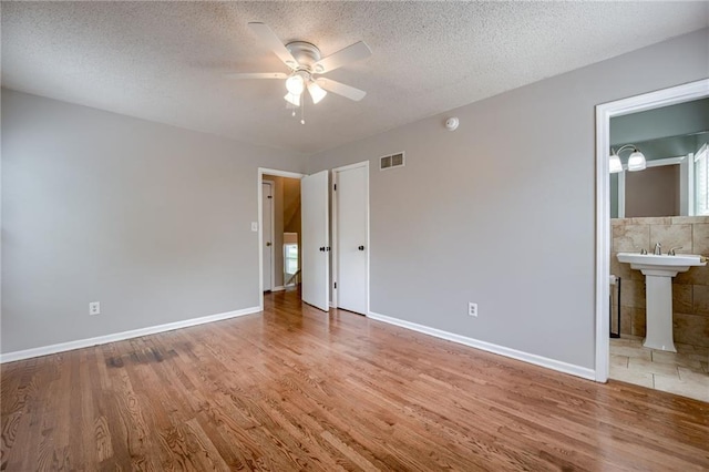 12800 W 100th St, Lenexa, KS 66215 - unfurnished bedroom featuring wood finished floors, a textured ceiling, baseboards, and connected bathroom