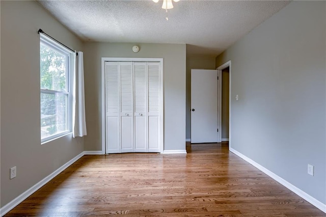 12800 W 100th St, Lenexa, KS 66215 - unfurnished bedroom featuring a textured ceiling, wood finished floors, a closet, and baseboards