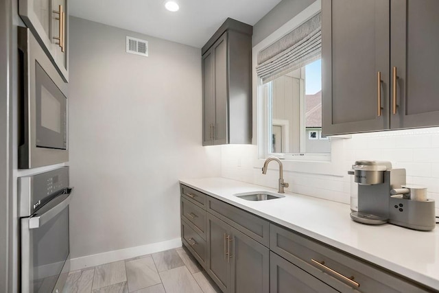 10300 W 174th St, Overland Park, KS 66221 - kitchen featuring a sink, appliances with stainless steel finishes, tasteful backsplash, baseboards, and gray cabinetry