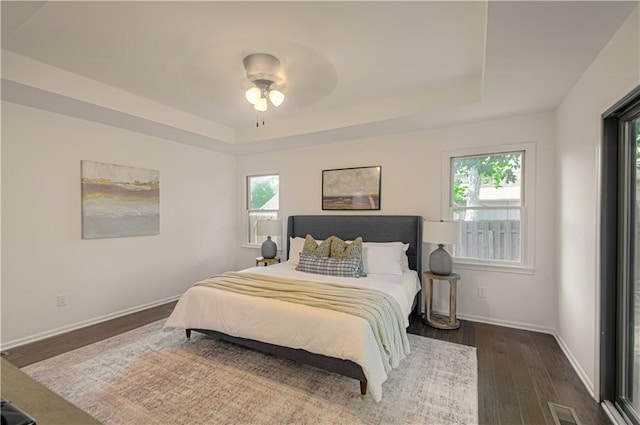 4300 W 112th St, Leawood, KS 66211 - bedroom featuring a tray ceiling, dark wood finished floors, multiple windows, and baseboards