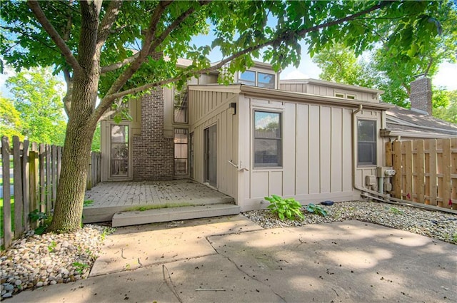 4300 W 112th St, Leawood, KS 66211 - view of front facade with board and batten siding, a patio, a fenced backyard, brick siding, and a chimney