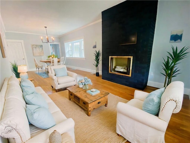 3208 E 31st St, Kansas City, MO 64128 - living area featuring wood finished floors, a chandelier, ornamental molding, and a glass covered fireplace