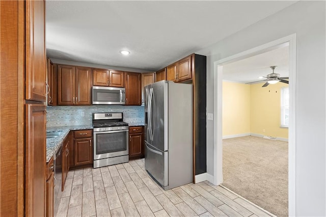 5317 NE 46th St, Kansas City, MO 64117 - kitchen with stainless steel appliances, light wood-style flooring, stone countertops, backsplash, and baseboards