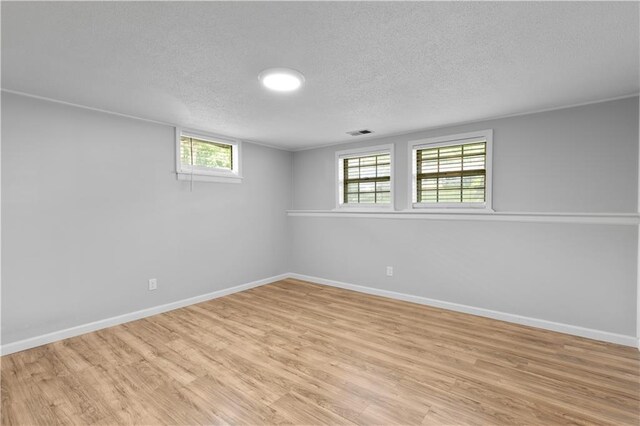 5317 NE 46th St, Kansas City, MO 64117 - below grade area featuring a textured ceiling, light wood-style flooring, and baseboards