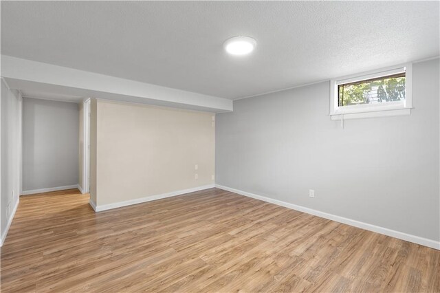 5317 NE 46th St, Kansas City, MO 64117 - below grade area with light wood-type flooring, baseboards, and a textured ceiling