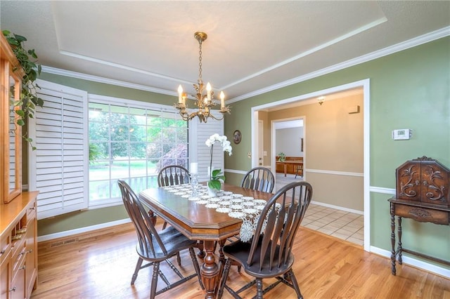 15243 Long St, Overland Park, KS 66221 - dining area featuring a tray ceiling, a chandelier, ornamental molding, light wood finished floors, and baseboards