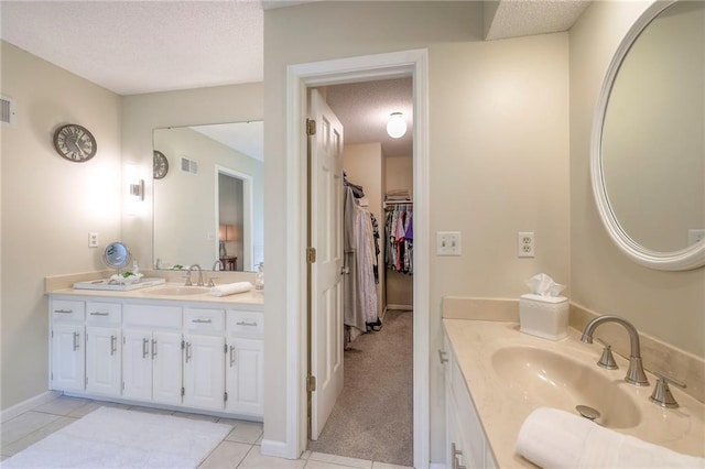 15243 Long St, Overland Park, KS 66221 - bathroom featuring a textured ceiling, two vanities, tile patterned flooring, a spacious closet, and baseboards