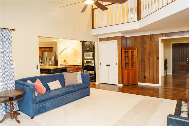204 NW Redwood Ct, Lees Summit, MO 64064 - living area featuring a towering ceiling, wooden walls, a ceiling fan, and dark wood-style flooring