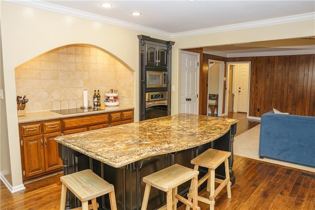 204 NW Redwood Ct, Lees Summit, MO 64064 - kitchen featuring stainless steel oven, black electric cooktop, built in microwave, decorative backsplash, and a breakfast bar