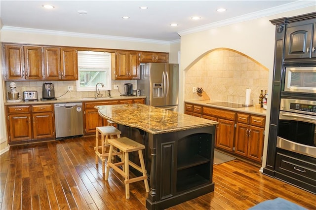 204 NW Redwood Ct, Lees Summit, MO 64064 - kitchen featuring appliances with stainless steel finishes, dark wood-style flooring, light stone counters, a center island, and tasteful backsplash