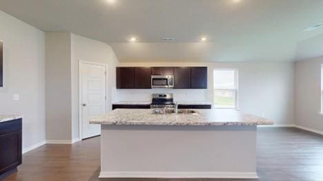575 W Lanesfield St, Gardner, KS 66030 - kitchen featuring stainless steel microwave, dark wood-style floors, a kitchen island with sink, dark brown cabinets, and light stone counters