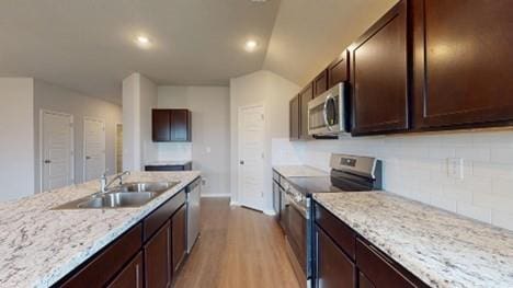 575 W Lanesfield St, Gardner, KS 66030 - kitchen with appliances with stainless steel finishes, light wood-style floors, tasteful backsplash, dark brown cabinets, and light stone countertops