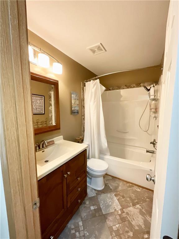 11601 N Manning Ave, Kansas City, MO 64157 - bathroom featuring vanity, shower / bathtub combination with curtain, and toilet