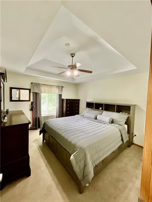 11601 N Manning Ave, Kansas City, MO 64157 - bedroom featuring a tray ceiling, light colored carpet, ceiling fan, and baseboards