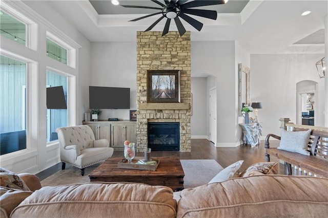 4313 Lakeview Ter, Basehor, KS 66007 - living room with a ceiling fan, a fireplace, wood finished floors, arched walkways, and a raised ceiling