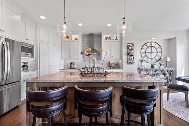 4313 Lakeview Ter, Basehor, KS 66007 - kitchen with appliances with stainless steel finishes, wall chimney range hood, backsplash, dark wood-style floors, and an island with sink