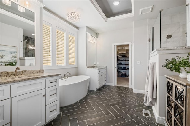 4313 Lakeview Ter, Basehor, KS 66007 - bathroom featuring two vanities, a shower stall, a soaking tub, a walk in closet, and baseboards