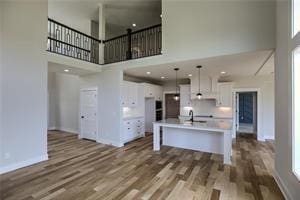 16247 S Kill Creek Rd, Gardner, KS 66030 - kitchen featuring a towering ceiling, wood finished floors, pendant lighting, light countertops, and white cabinets