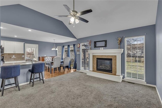3708 N 112th St, Kansas City, KS 66109 - living area with light carpet, vaulted ceiling, a ceiling fan, a glass covered fireplace, and baseboards