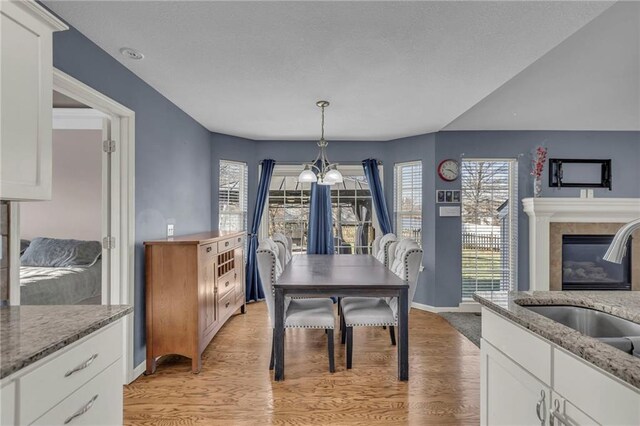 3708 N 112th St, Kansas City, KS 66109 - dining area featuring a chandelier, light wood finished floors, a tiled fireplace, and baseboards