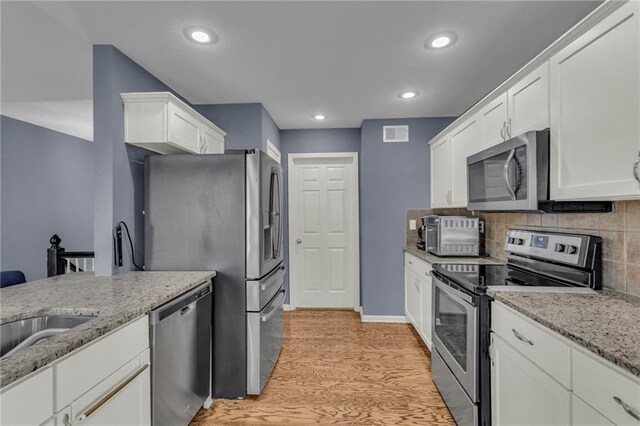 3708 N 112th St, Kansas City, KS 66109 - kitchen with appliances with stainless steel finishes, light wood-type flooring, white cabinets, light stone counters, and recessed lighting