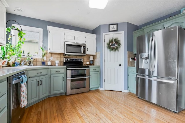 616 N Winwood Ter, Gardner, KS 66030 - kitchen with appliances with stainless steel finishes, light wood-type flooring, light countertops, backsplash, and white cabinets