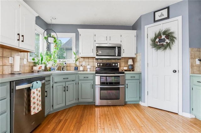 616 N Winwood Ter, Gardner, KS 66030 - kitchen featuring stainless steel appliances, light wood-type flooring, white cabinets, light countertops, and tasteful backsplash