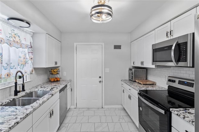 10538 Cleveland Ave, Kansas City, MO 64137 - kitchen with appliances with stainless steel finishes, light marble finish flooring, white cabinets, and decorative backsplash