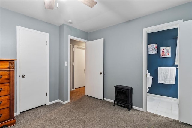 10538 Cleveland Ave, Kansas City, MO 64137 - unfurnished bedroom with carpet floors, a wood stove, connected bathroom, and a ceiling fan