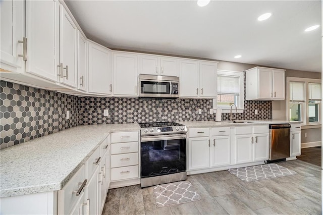 1025 S Park Ave, Independence, MO 64050 - kitchen with appliances with stainless steel finishes, white cabinetry, tasteful backsplash, light wood finished floors, and recessed lighting