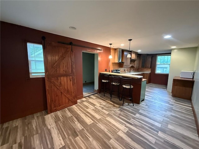 347 Walnut St, Kidder, MO 64649 - kitchen featuring a barn door, a peninsula, light wood finished floors, light countertops, and a breakfast bar area