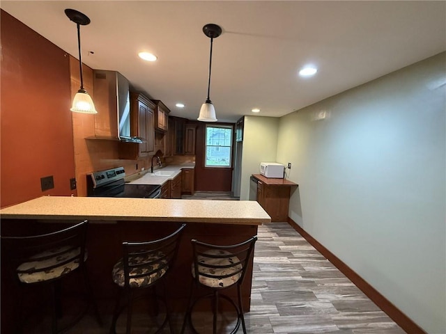 347 Walnut St, Kidder, MO 64649 - kitchen with range with electric stovetop, light countertops, a peninsula, a breakfast bar area, and a sink