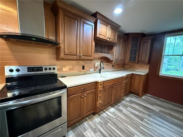 347 Walnut St, Kidder, MO 64649 - kitchen with stainless steel range with electric stovetop, wall chimney range hood, a sink, light countertops, and decorative backsplash