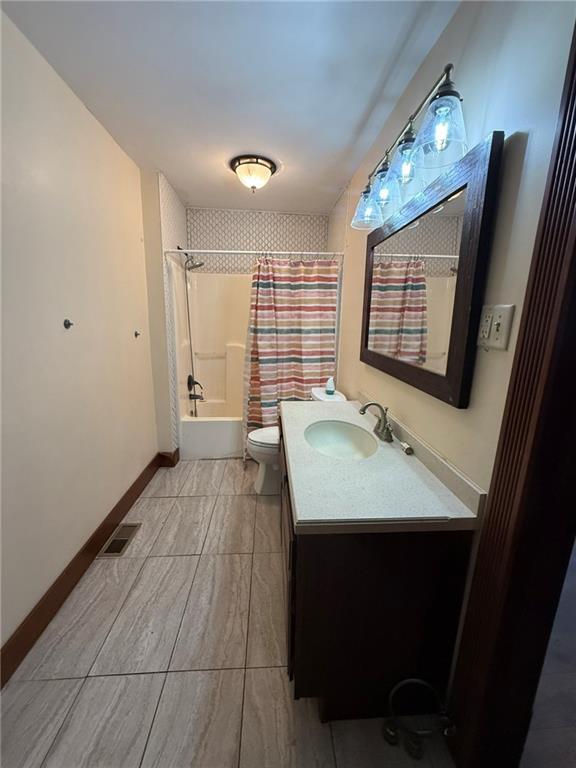 347 Walnut St, Kidder, MO 64649 - full bath featuring vanity, shower / tub combo with curtain, toilet, and baseboards