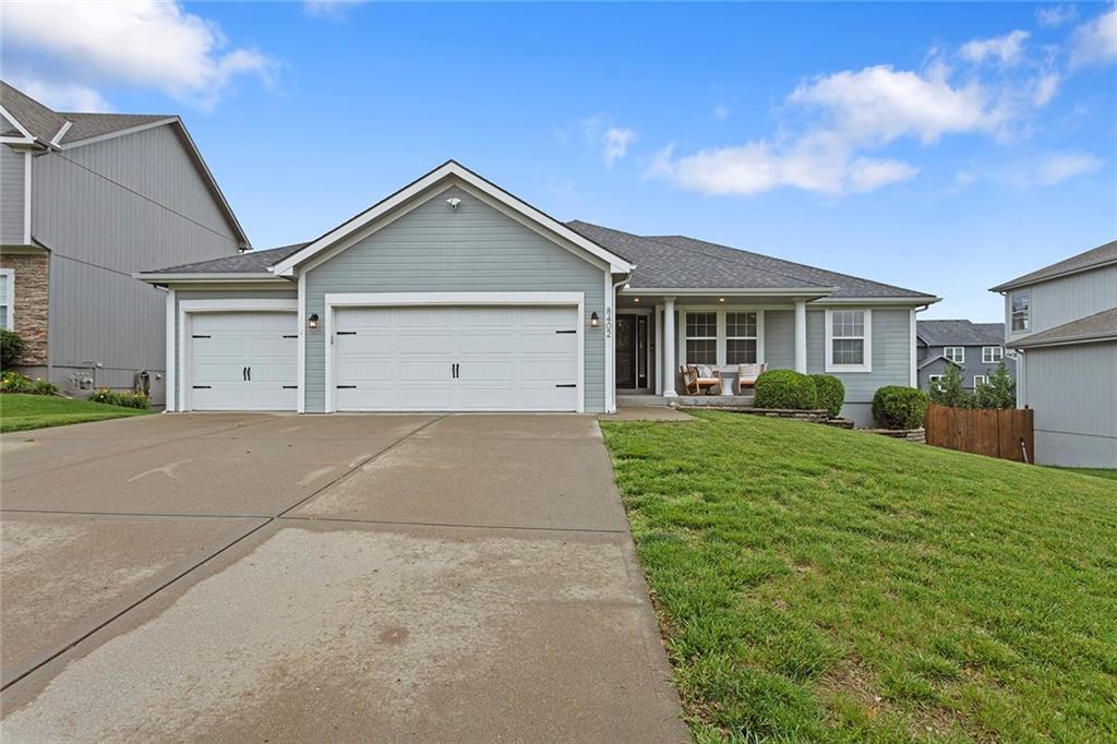 8402 NE 102nd St, Kansas City, MO 64157 - view of front facade with a garage, concrete driveway, and covered porch