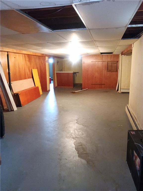 4426 Shrine Park Rd, Leavenworth, KS 66048 - finished basement with a baseboard heating unit, a paneled ceiling, and wood walls