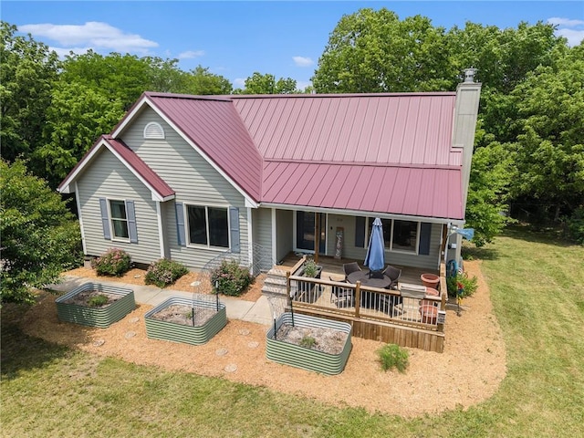 310 E Seybold Rd, Excelsior Springs, MO 64024 - rear view of house featuring a garden, a chimney, a lawn, a standing seam roof, and metal roof