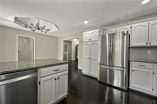 1609 NE Jade Ct, Lees Summit, MO 64086 - kitchen with stainless steel appliances, recessed lighting, white cabinets, a textured ceiling, and dark stone counters