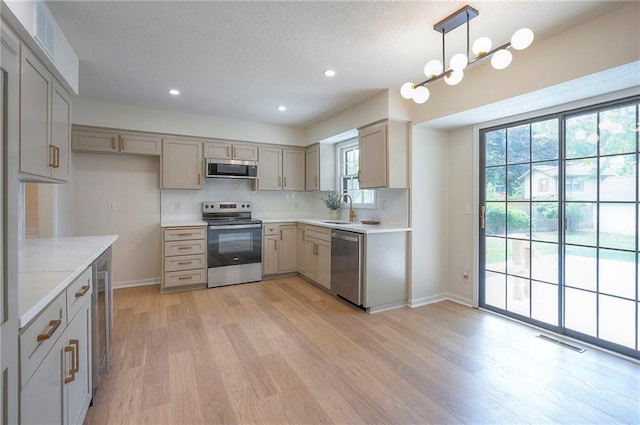 9100 Dearborn St, Overland Park, KS 66207 - kitchen with stainless steel appliances, light wood-style flooring, gray cabinetry, recessed lighting, and a textured ceiling