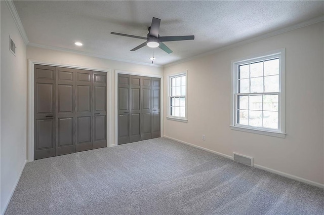 9100 Dearborn St, Overland Park, KS 66207 - unfurnished bedroom with two closets, crown molding, carpet, ceiling fan, and a textured ceiling