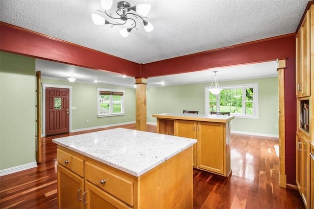 4188 Country Squire Ln, Oak Grove, MO 64075 - kitchen with a kitchen island, dark wood finished floors, a textured ceiling, baseboards, and decorative columns