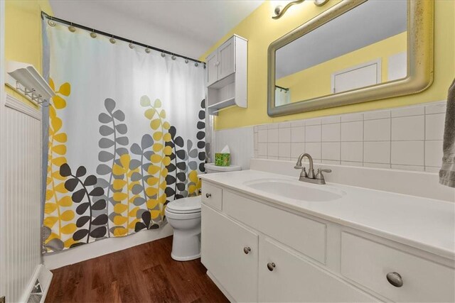 4400 Elledge Dr, Roeland Park, KS 66205 - full bath with wood finished floors, vanity, toilet, wainscoting, and a shower with shower curtain
