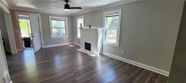 5118 Wabash Ave, Kansas City, MO 64130 - unfurnished living room featuring crown molding, dark wood-style floors, baseboards, a ceiling fan, and a brick fireplace
